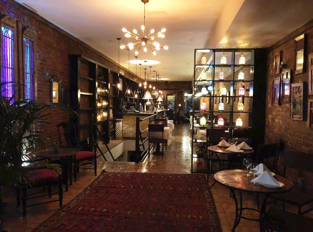 Midtown West dining room — brick walls, brass chandeliers, Moroccan lanterns